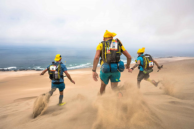 Photo of three participants of the HMDS with their UltraBag 20L going down a dune