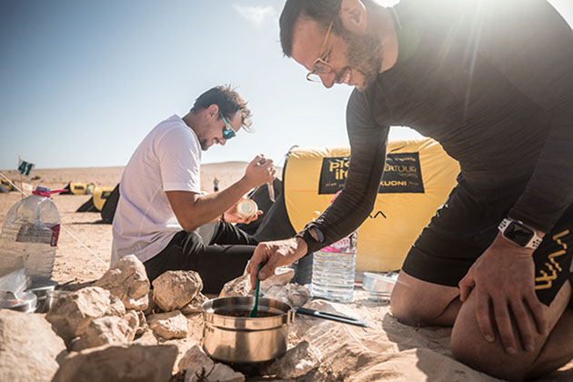 Two men preparing food at the bivouac