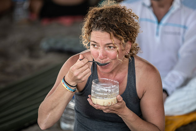 A woman eating in a bowl made from a plastic bottle
